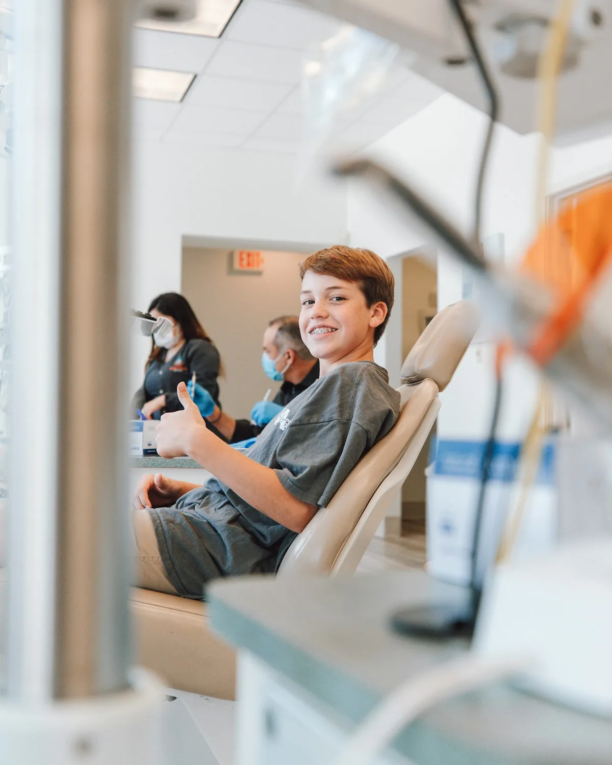Smiling young dental patient giving a thumbs up in the treatment chair